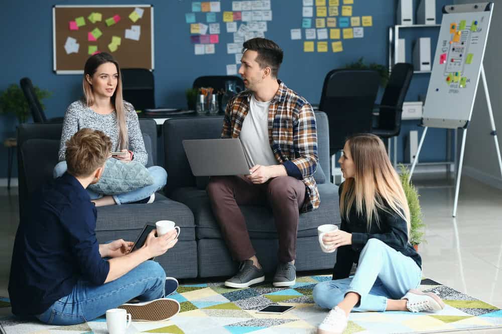 Vier junge Arbeitskollegen und Kolleginnen beraten sich in einem Büro.
