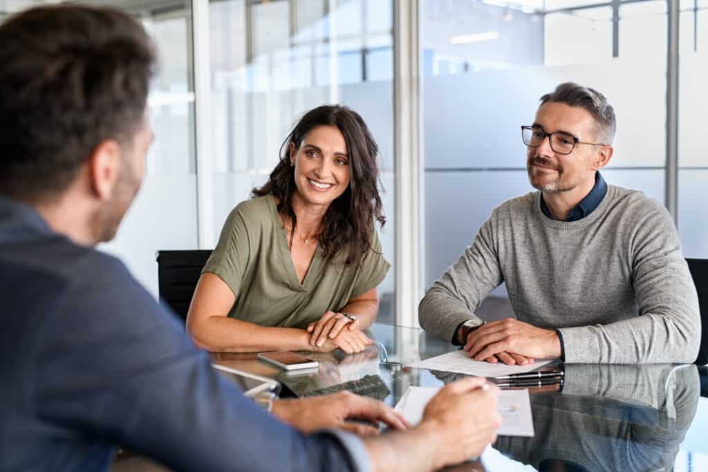 A smiling middle-aged couple is being advised by an employee in a modern office.
