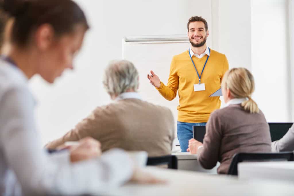 Ein fröhlicher Mitarbeiter hält seinen Kollegen und Kolleginnen eine Präsentation.